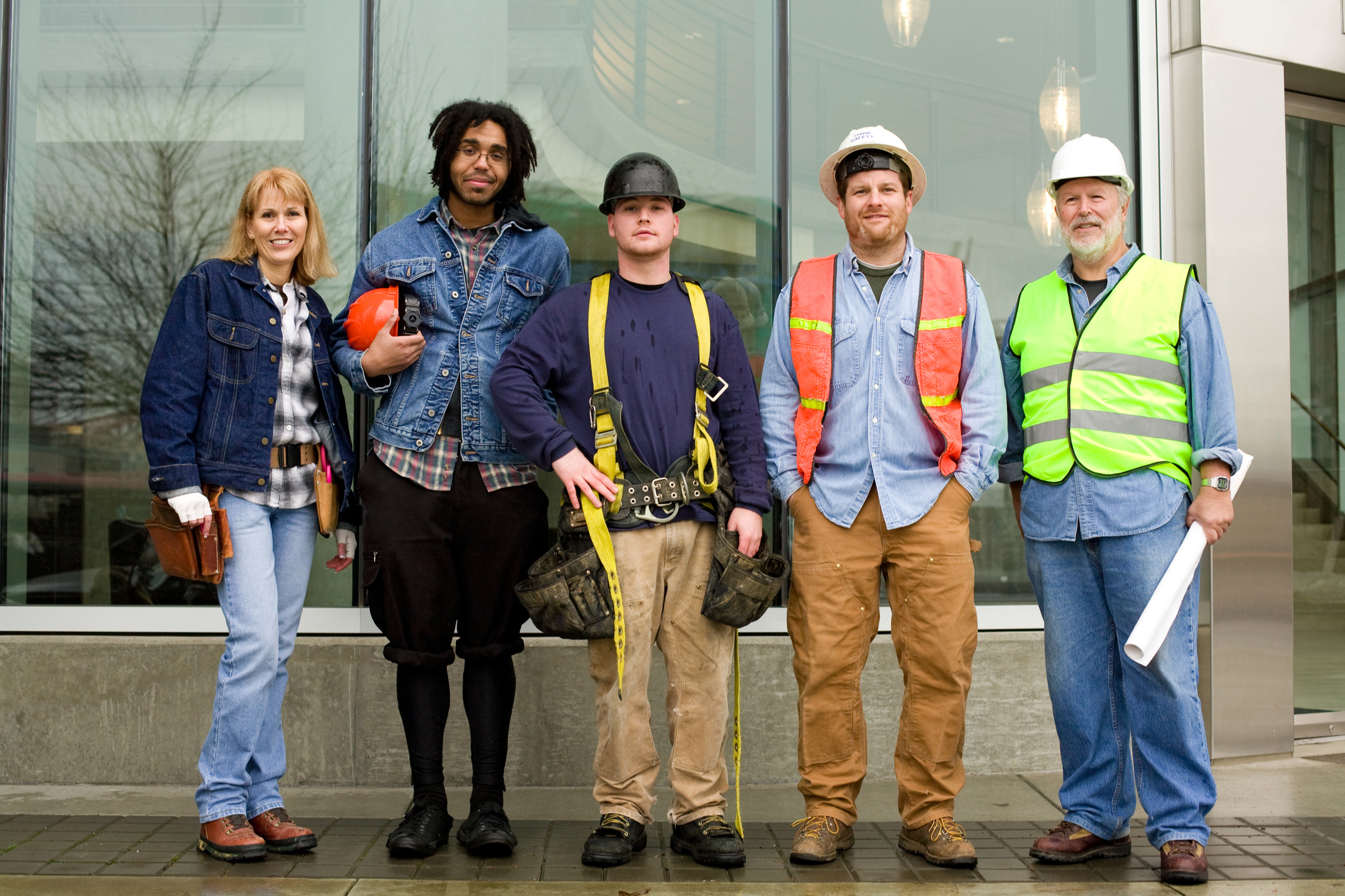 A group of contstruction workers, all eliglbe for WA Cares benefits, stand and smile at the camera. They are of various identities, presentations, and ages.