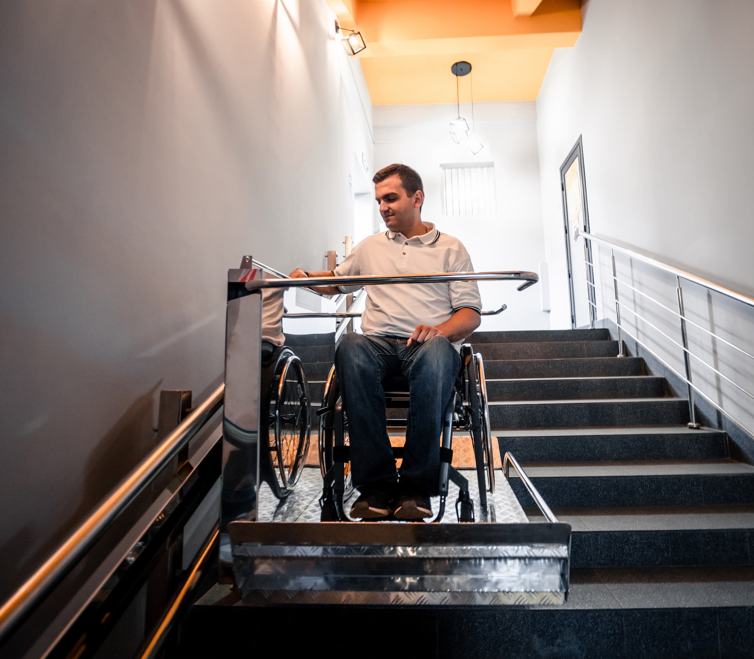 A white middle aged person uses a wheelchair ramp inside their modern house.